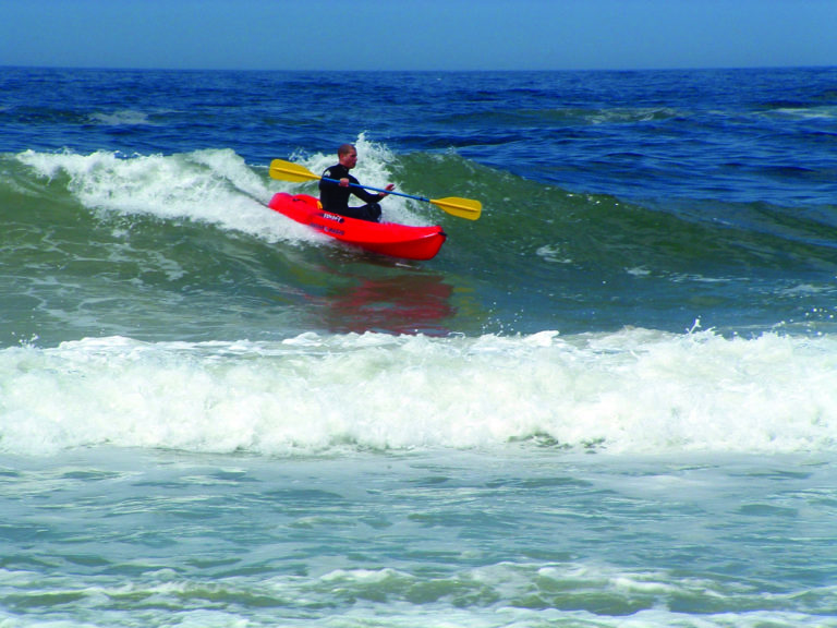 man paddling a kayak on a wave