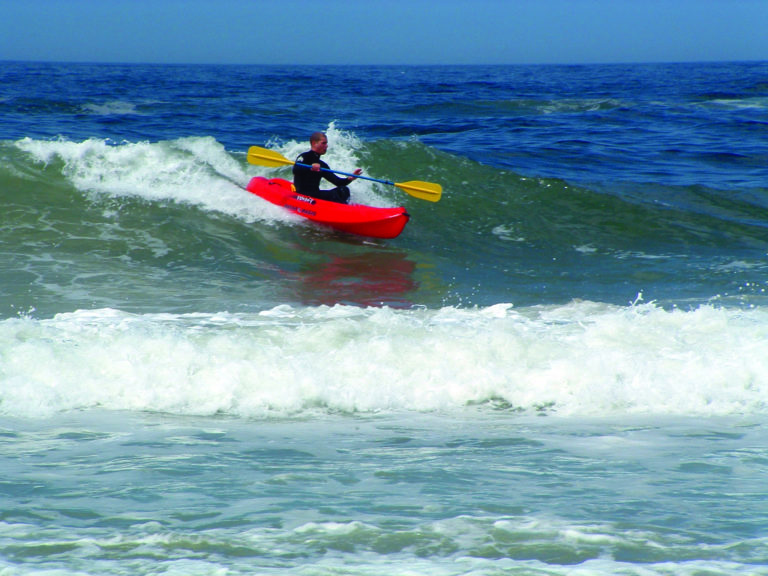 man paddling a kayak on a wave