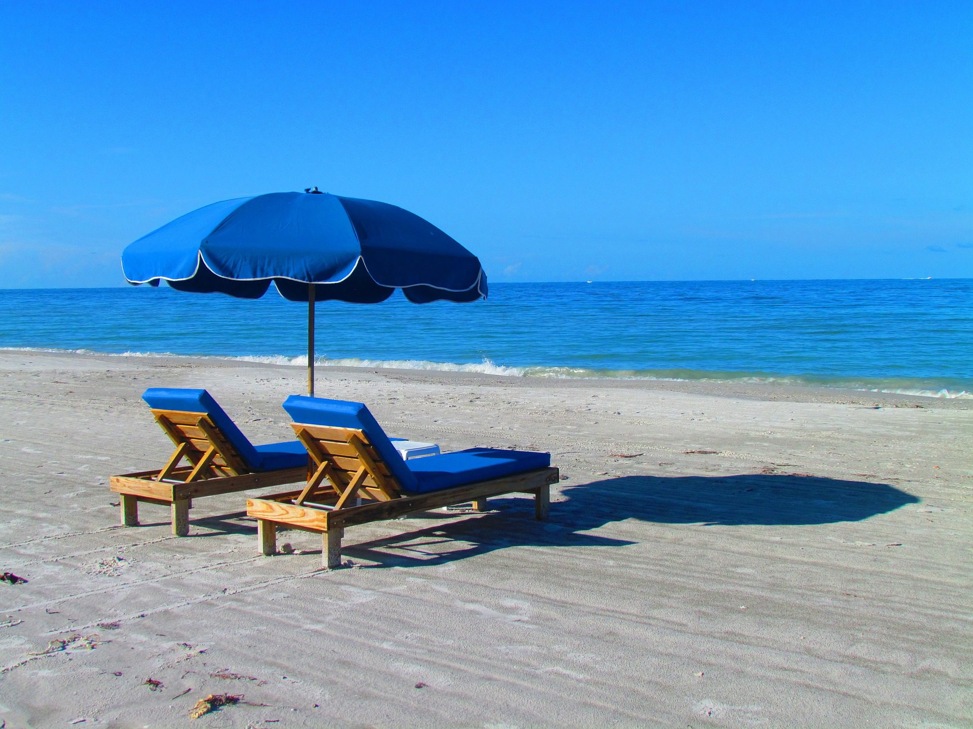 Two beach chairs and an umbrella set up on the beach.